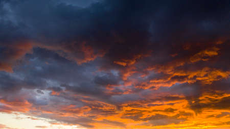 The sun gives up her last light of the day awash over the cloudsの写真素材