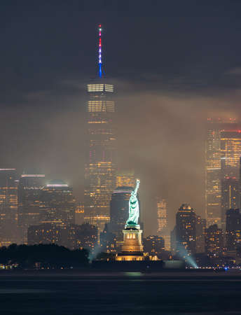 The park lights illuminate Lady Liberty amidst fireworks smoke on July 4th, 2019の写真素材