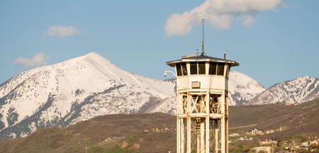 Blue skies and snow covered mountains stand behind a prison guard watchtowerのeditorial素材