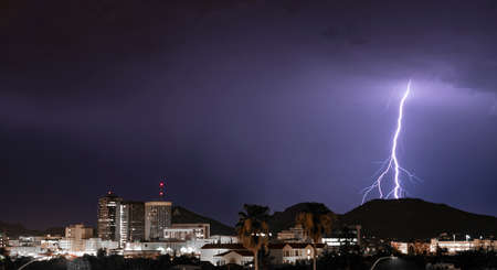 Purple Blue light illuminates the sky over the buildings homes and hills around Tucson Arizonaの写真素材