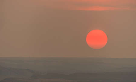 There are just a few minutes left in the day as the large orange Sun orb lowers towards the horizonの写真素材