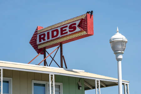 A red sign with arrow pointing at the boardwalk where carnival rides are availableの写真素材