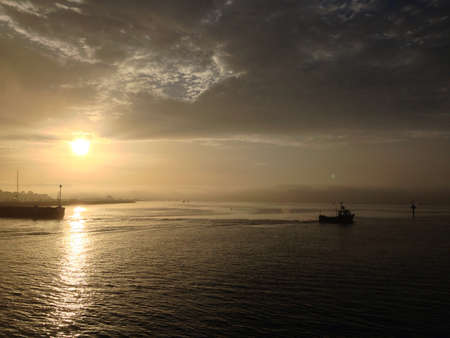 Sunrise at Poole harbour with a small fishing boat passing. の素材