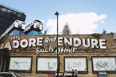 wall, train, letters, art, board, design, sidewalk, pole, light, bulb, bench, people, walking,...