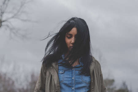 people, woman, lady, windy, hair, alone, bokeh, blur, plants, tree, branch, sky, clouds, jacket,...