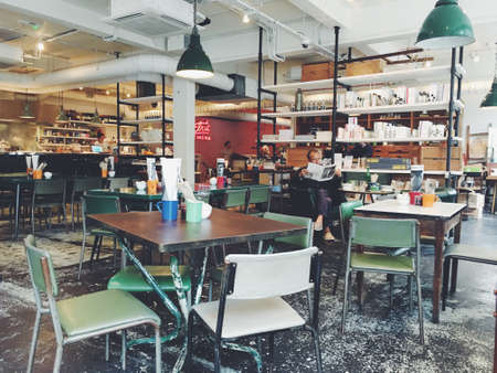 table, chairs, indoor, inside, people, man, reading, newspaper, bar, restaurant, business