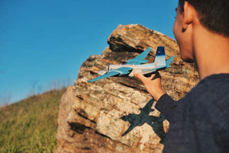 airplane, airline, toy, blue, sky,green, grass, rocks, cliff, people, man