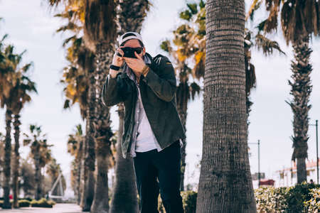photographer,  camera,  outdoors,  palm trees,  action,  male,  person,  travel,  vacation,  tourism