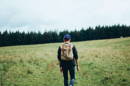 Man Walking on Grass Field Leading to Trees