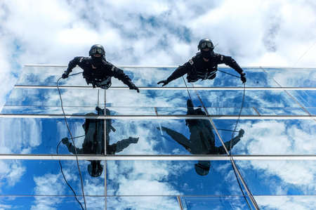 Two People on Building Glass Wall Under Cloudy Sky