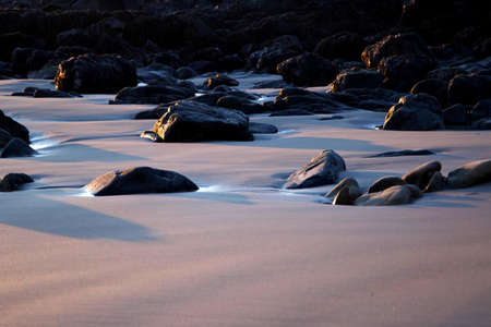 Black Rocks on Sand during Daytime