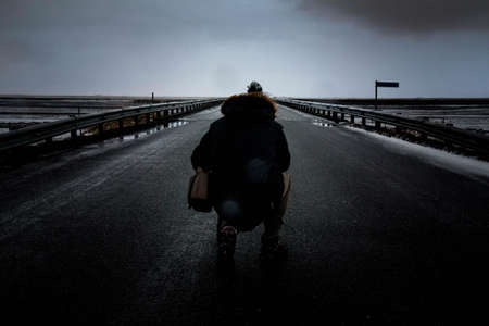Person Kneeling on Concrete Pavement Wearing Parka Jacket