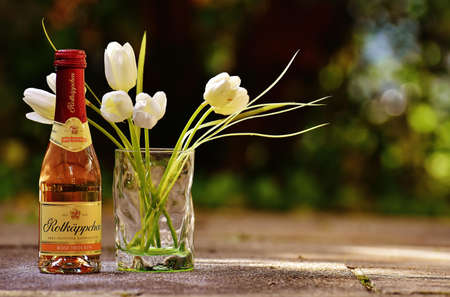 White Tulips in Clear Glass Beside Labeled Bottl