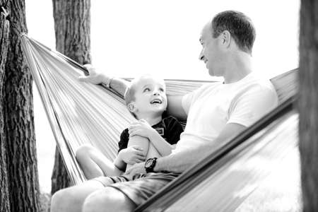 Grayscale Photo of Man and Child Sitting on Hammock