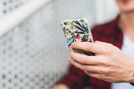 Person Holding Smartphone With White and Green Floral Case
