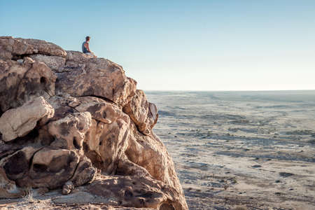 Man Sitting On Rock Cliff