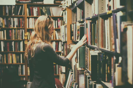Woman in Black Long-sleeved Looking for Books in Library