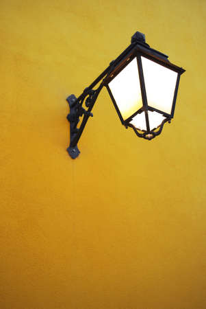 Bright light from an old street lamp in a yellow wall.の写真素材