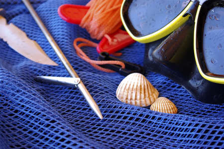 Details of scuba-diving and spear-fishing gear over a blue fishing net bagの写真素材
