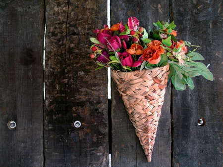 Basket with flowers attached in a old wooden fence.