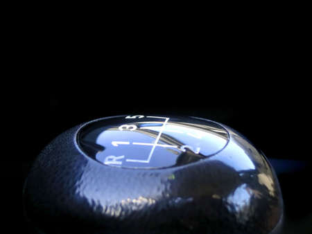 Macro detail of a vehicle's gear stick handle over black background