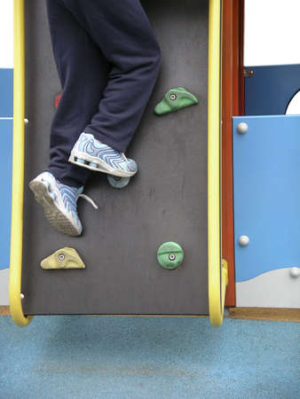 Photo detail of a child climbing a wall in a playground.