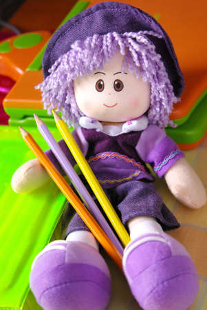 Purple wool smiling doll with colorful pencilsの写真素材