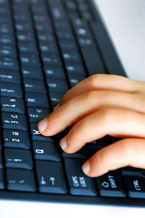 Close-up of child's hand typing on laptop keyboard
