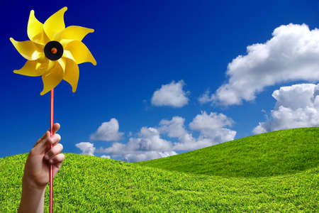 Green grass hills and childs hand holding a yellow spinnerの写真素材