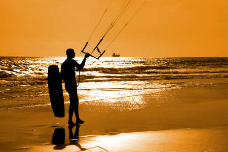Kitesurfer silhouette moving on the sand an holding equipmentの写真素材