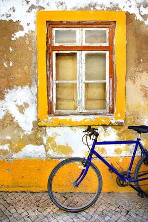 Bicycle in front of a window of a old white and yellow houseの写真素材
