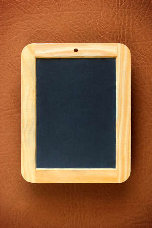 Little old blackboard with wooden frame over brown leather