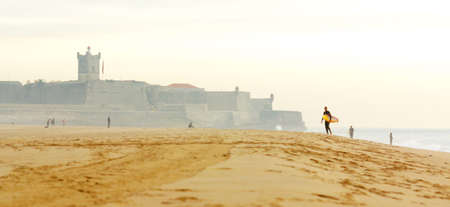 Beach with coastal fortification and a surfer in the distanceの写真素材