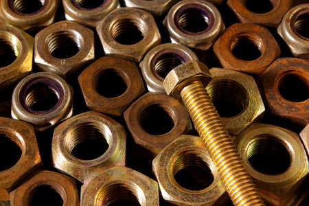 Background of assorted old rusty nuts with a screw on topの写真素材