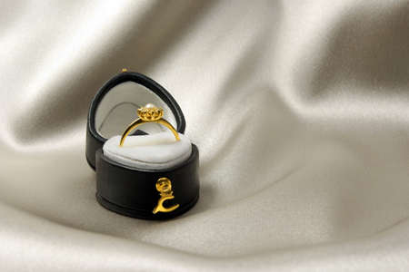 Golden engagement ring in a heart-shaped box over satin