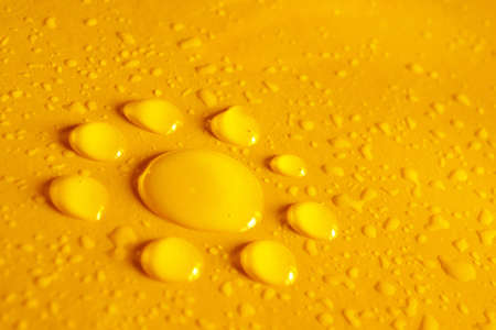 Water drops with the shape of a flower in yellow backgroundの写真素材
