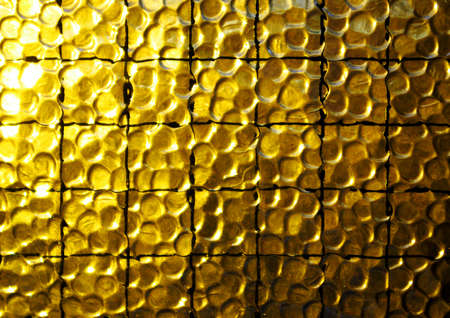 Background of a yellow opaque glass with wire netの写真素材