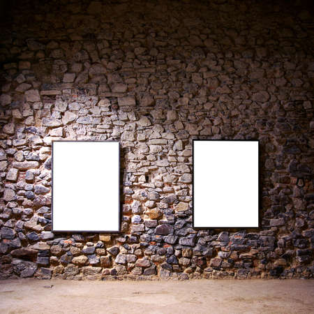 Two empty frames attached to a stone wall in a gallery roomの写真素材
