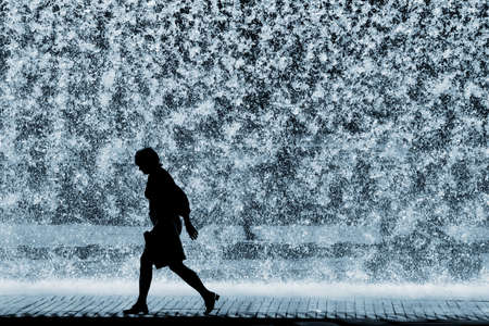 Woman's silhouette over heavy waterfall backgroundの写真素材