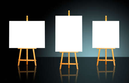 Three blank white canvas on easels over a dark backgroundの写真素材
