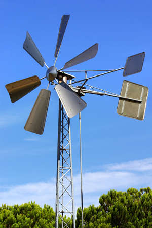 Vintage metallic windmill against blue skyの写真素材