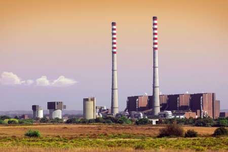 A thermoelectric plant with big chimneys in a rural landscape at sunsetのeditorial素材