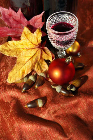 Vintage red wine glass and bottle with fall and Christmas decorationsの写真素材