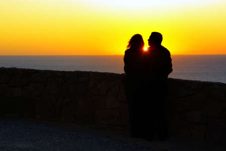 Silhouette of a loving couple against a beautiful sunsetの写真素材
