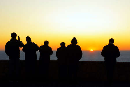Silhouette of a group of tourists looking at the sunsetの写真素材