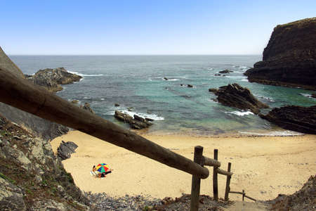 little beach with wooden stairway and surrounded by rocky cliffs の写真素材