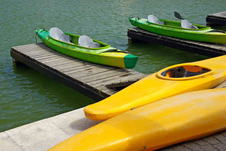 Two green and two yellow kayaks resting in a pier by the riverの写真素材
