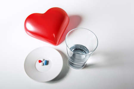 Concept image of glass of water and medical pills for heart diseasesの写真素材