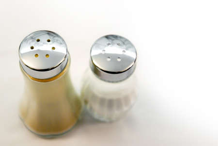 closeup of salt and pepper bottles on a table with white tableclothの写真素材