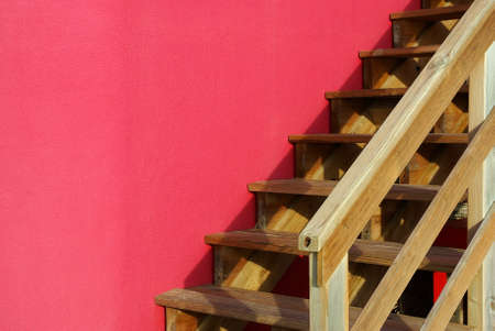 Detail of an outdoor wooden stairway against a pink wallの写真素材